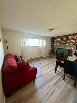 a living room with a red couch and a table at Beautiful home near City centre! in Kitimat