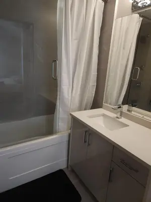a bathroom with a sink and a shower with a mirror at Central 2-Bedroom Townhouse Oak st in Vancouver