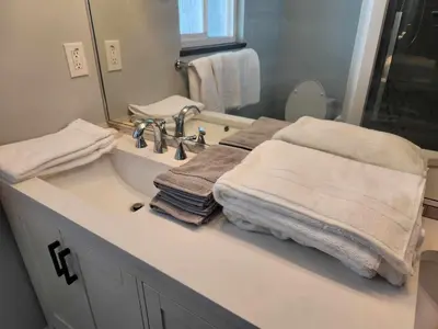 a bathroom with a sink with towels and a mirror at Central Townhouse Richards Street in Vancouver