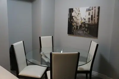 a glass dining room table with four chairs and a painting at YYC : 2-Bedroom City Apartment in Calgary