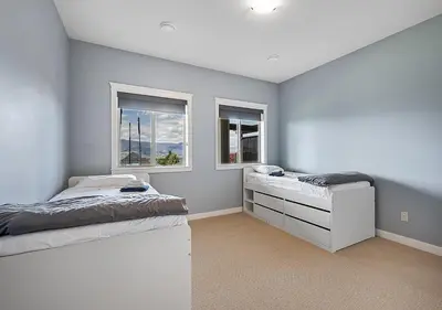 a bedroom with two beds and two windows at Full House with Amazing Okanagan Views and Hot Tub in Kelowna