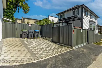 a fence with three trash cans in front of a house at Budget friendly 2-Bed 1-Bath Suite in New Westminster