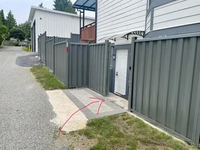 a fence next to a house with a door at Budget friendly 2-Bed 1-Bath Suite in New Westminster