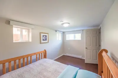a bedroom with a bed and a window and a door at 4 Bedroom Semi-basement Suite in Burnaby Metrotown in Burnaby