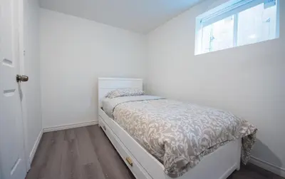 a small bedroom with a bed with a window at 4 Bedroom Semi-basement Suite in Burnaby Metrotown in Burnaby