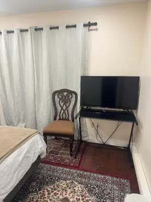 a bedroom with a tv and a chair and a bed at Dunbar Guest Home close downtown Vancouver, UBC and store in Vancouver
