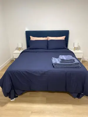 a blue bed with blue sheets and two night stands at Oceanside 2 Bedroom Suite in Royal Bay-Free Nespresso Coffee with Welcome Treats in Colwood