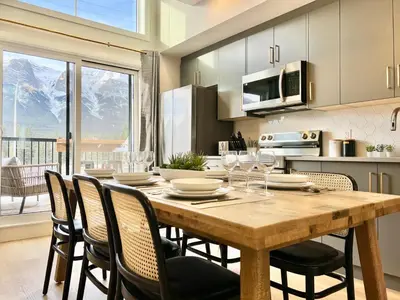 a kitchen with a wooden table with chairs and a dining room at Stunning View New Townhome Sleeps 11 AC and Hot Tub in Canmore