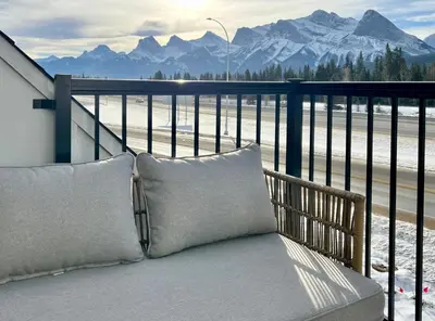 a bench on a balcony with a view of mountains at Stunning View New Townhome Sleeps 11 AC and Hot Tub in Canmore