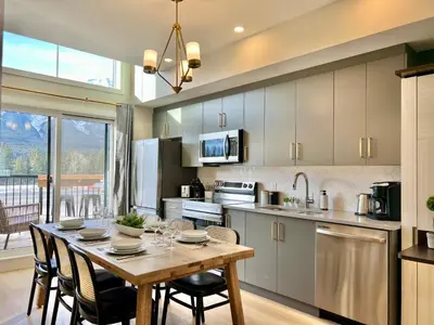 a kitchen with a wooden table with chairs and a dining room at Stunning View New Townhome Sleeps 11 AC and Hot Tub in Canmore