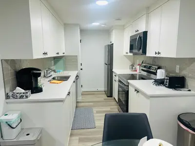 a kitchen with white cabinets and white counters at 2 Bedroom snug retreat in Livingston Calgary Alberta in Calgary