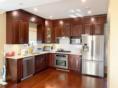 a kitchen with wooden cabinets and a stainless steel refrigerator at Cozy stay in Cental Vancouver in Vancouver