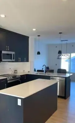 a kitchen with black cabinets and a counter top at Bedroom with TV in Upland E in Edmonton