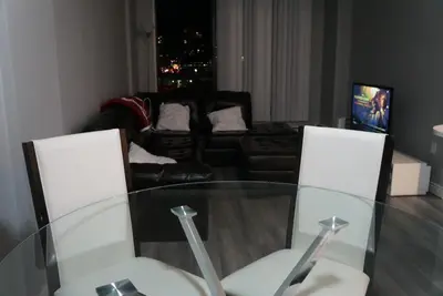 a glass table and two white chairs in a living room at Wildrose : 2-Bedroom City Apartment in Calgary
