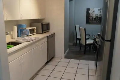 a kitchen with a refrigerator and a table with chairs at Wildrose : 2-Bedroom City Apartment in Calgary