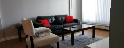 a living room with a couch and a table and a chair at Wildrose : 2-Bedroom City Apartment in Calgary