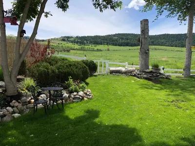 a garden with a table and chairs in the grass at Country Cottage B&B in Vernon