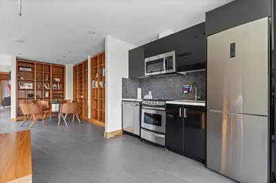 a kitchen with stainless steel appliances and a dining room at Elegant, Comfy & Sophisticated MetroLux Downtown Suite in Calgary