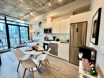 a kitchen and living room with a table and chairs at Elegant, Comfy & Sophisticated MetroLux Downtown Suite in Calgary