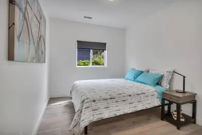 a white bedroom with a bed and a window at Pure Paradise in Prince George