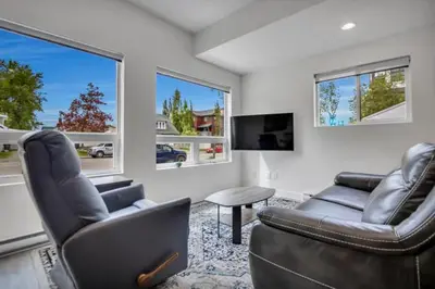 a living room with two chairs and a couch and a tv at Pure Paradise in Prince George
