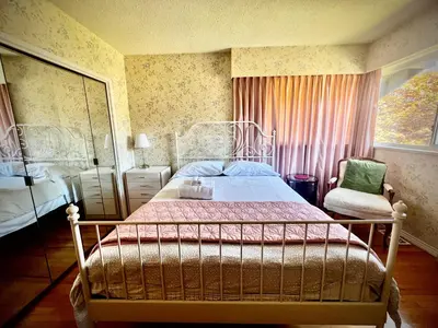 a bedroom with a bed and a chair and a window at Spacious place Close to UBC -1 in Vancouver