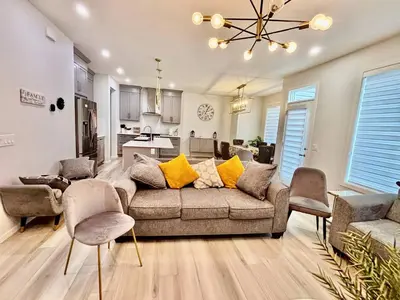 a living room with a couch and chairs and a kitchen at Zillion’s Joy in Calgary