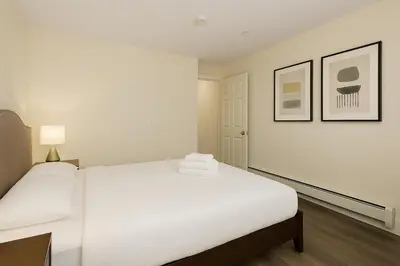 a white room with a bed and two pictures at Spacious 4BD Home in Vancouver in Vancouver
