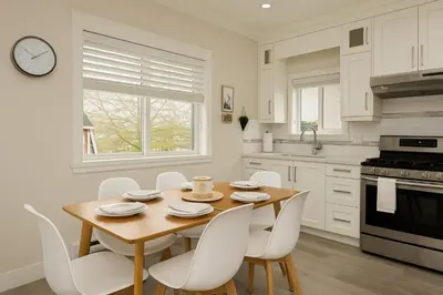 a kitchen with a wooden table and white chairs at Spacious 4BD Home in Vancouver in Vancouver