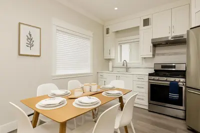 a kitchen with a wooden table and white cabinets at Spacious 4BD Home in Vancouver in Vancouver