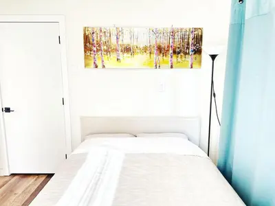 a bedroom with a bed and a painting on the wall at 5 Min to Southgate Mall and U of A, Bright and Private, Cool Summer Stay in Edmonton