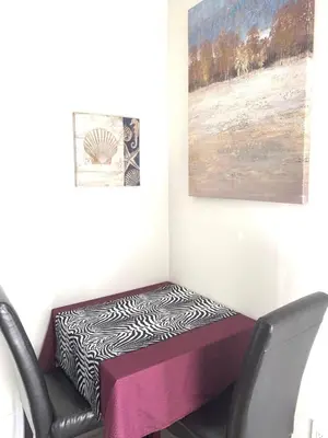 a room with a chair and a table and a painting at 5 Min to Southgate Mall and U of A, Bright and Private, Cool Summer Stay in Edmonton