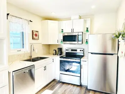 a kitchen with white cabinets and a stainless steel refrigerator at 5 Min to Southgate Mall and U of A, Bright and Private, Cool Summer Stay in Edmonton