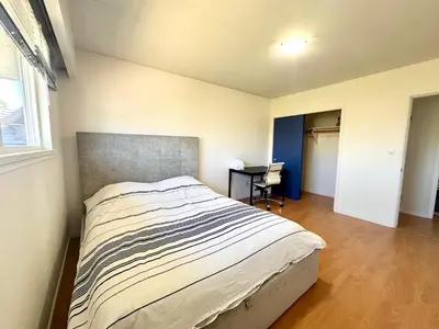 a bedroom with a bed and a desk in it at Spacious 5 Bedroom House Near YVR Airport, Transit & Shopping in Richmond