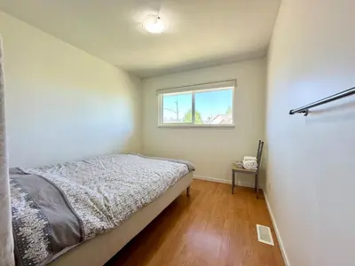 a small bedroom with a bed and a window at Spacious 5 Bedroom House Near YVR Airport, Transit & Shopping in Richmond