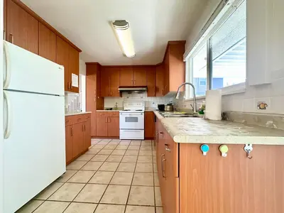 a kitchen with wooden cabinets and a white refrigerator at Spacious 5 Bedroom House Near YVR Airport, Transit & Shopping in Richmond