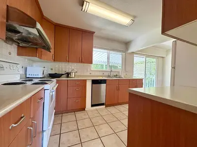 a large kitchen with wooden cabinets and white appliances at 2 Bedrooms Garden Suite with Living Room, Kitchen and Laundry near YVR Airport, Transit and Shopping Mall in Richmond