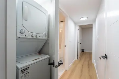 a bathroom with a washer and dryer and a hallway at New 1 bdr basement apartment in Calgary