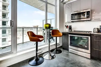 a kitchen with two bar stools in front of a window at Modern 1BR plus Den Condo for 4 guests Great Views and Balcony in Calgary