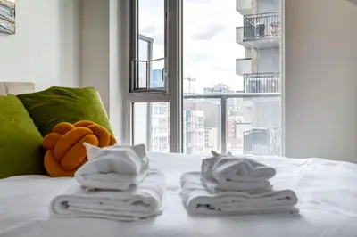 a bed with towels on top of it with a window at Modern 1BR plus Den Condo for 4 guests Great Views and Balcony in Calgary