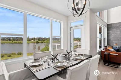 a dining room with a table and chairs and windows at Luxurious Detached House with Private Garage, Lake View, Central AC & More in Airdrie