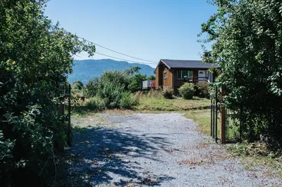 a dirt road leading to a house with a fence at Serene 3BR Cabin on 8 Acre Farm in Mission City