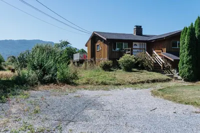 a house with a gravel driveway in front of it at Serene 3BR Cabin on 8 Acre Farm in Mission City