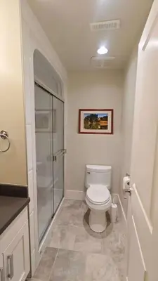 a bathroom with a toilet and a glass shower at Bright 3-Bedroom Basement Suite with Separate Entrance in Burnaby