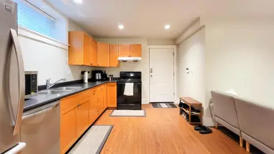 a small kitchen with wooden cabinets and a sink at Bright 3-Bedroom Basement Suite with Separate Entrance in Burnaby