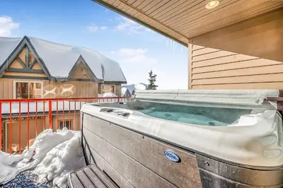 a hot tub on the side of a house in the snow at Treetops Ski Luxury Townhouse in Big White