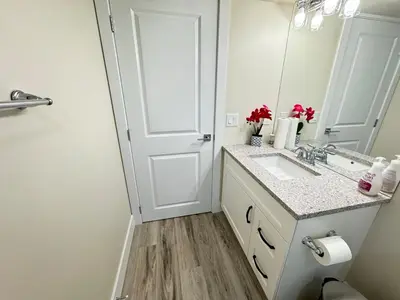 a white bathroom with a sink and a mirror at Annas Suites Rental in Bélanger