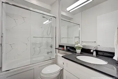 a white bathroom with a sink and a shower at Queens Suite in West Vancouver