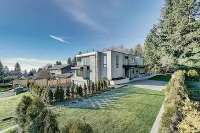a house with a large yard with trees at Queens Suite in West Vancouver