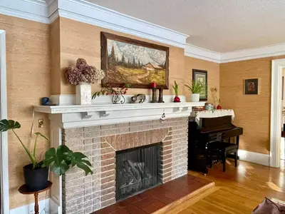 a living room with a brick fireplace and a piano at \u6e29\u54e5\u534e\u6e29\u897f\u522b\u588534 in Vancouver
